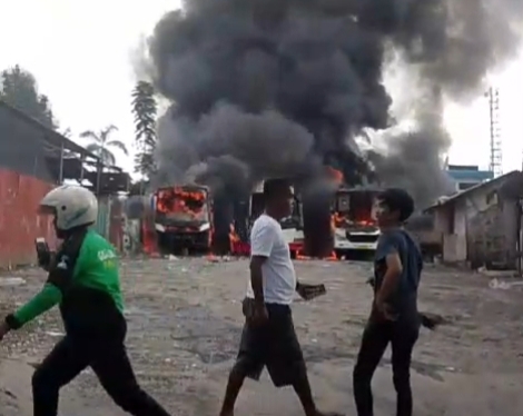 Warga berupaya memadamkan api yang menjalar tiga unit bus pariwisata di Pool Jalan Ngunban Surbakti, Kamis (30/1/2025) sore.